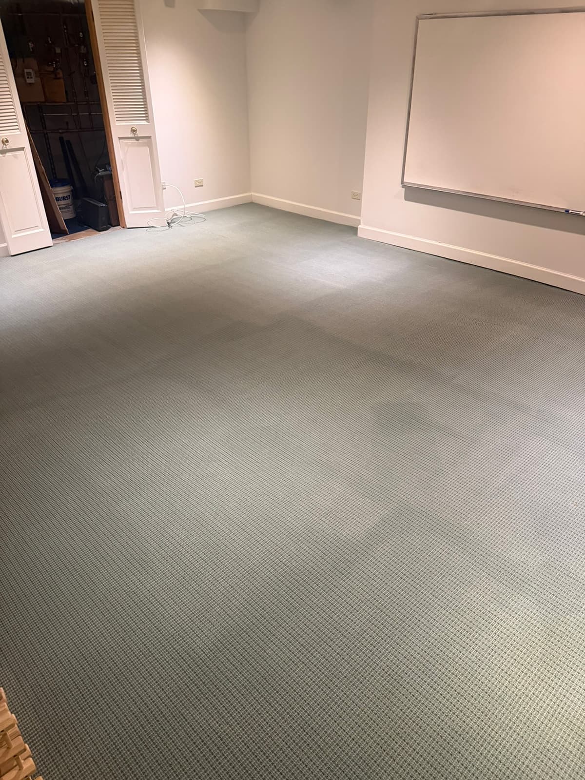 An empty office room with low-pile carpet cleaned end to end, a whiteboard on the far wall