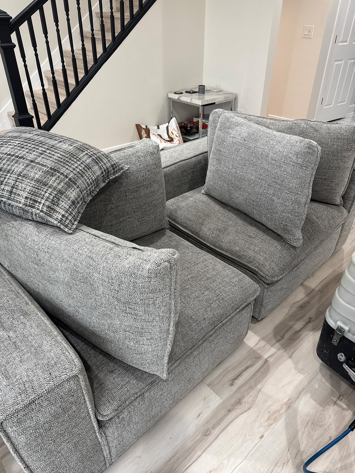 Two upholstered chairs cleaned and set beside a staircase with the extractor alongside