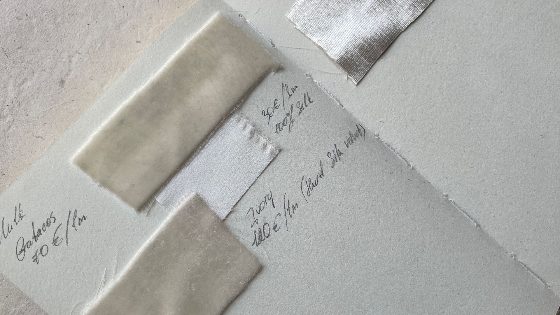 An open sample book of upholstery fabric swatches with handwritten labels